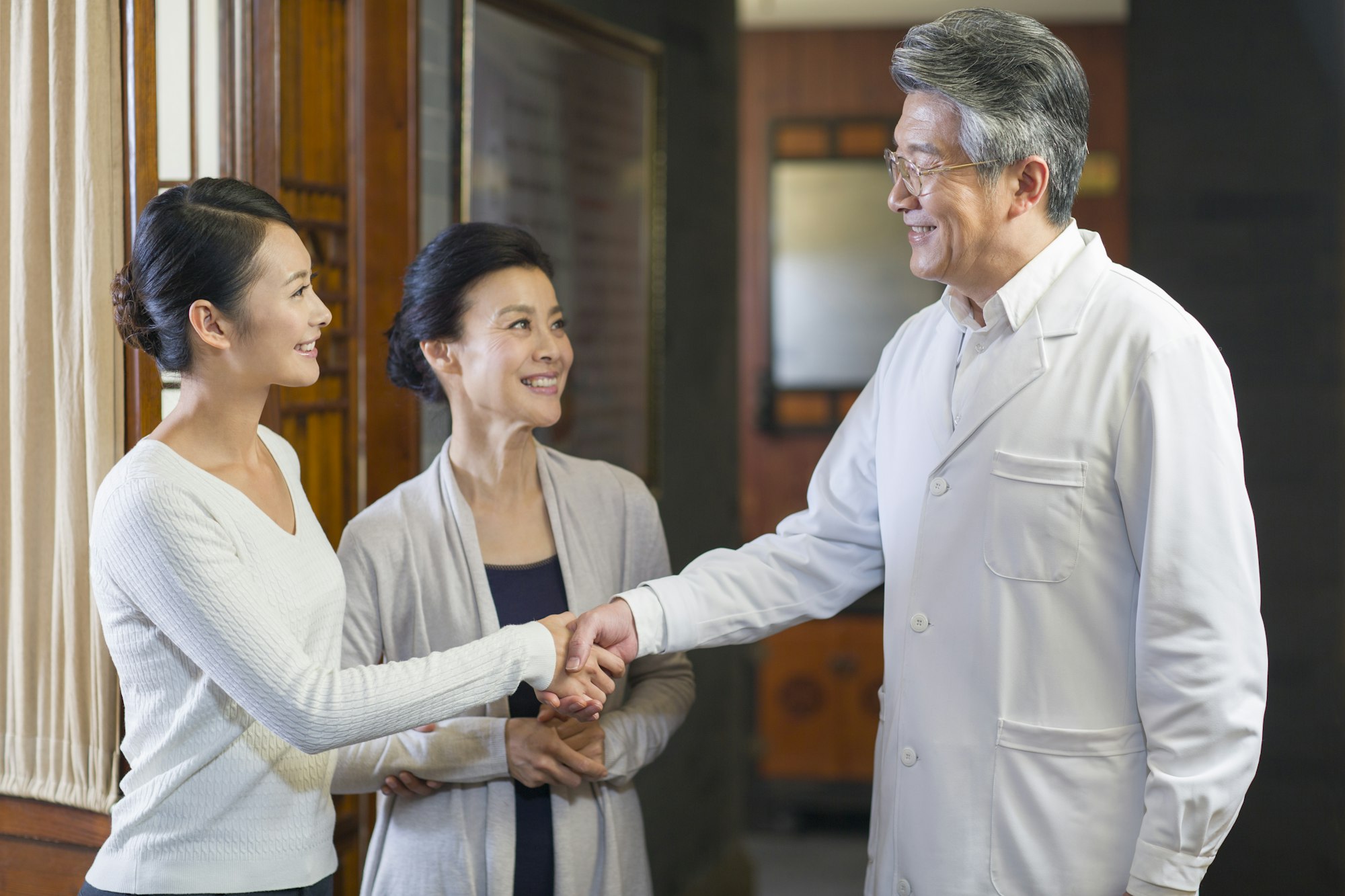 Senior Chinese doctor shaking hands with patient